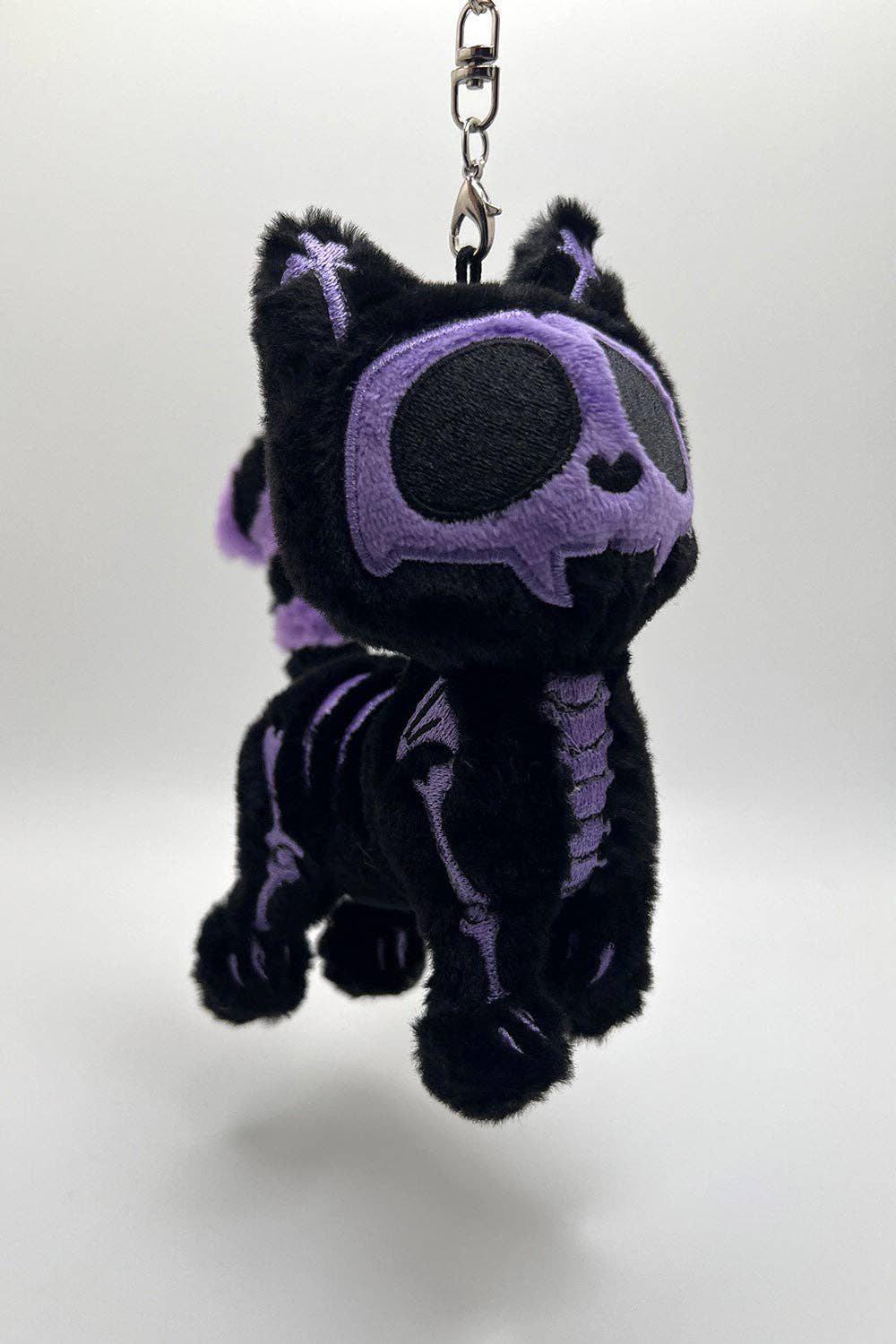 Black and purple plush keychain with a skeleton design on a white background
