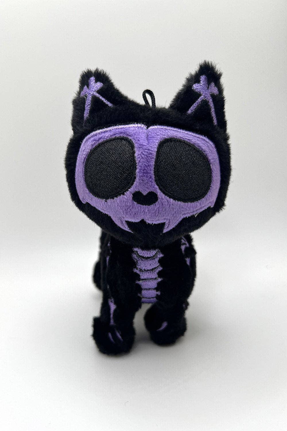 Black plush toy with purple skeleton design on a white background