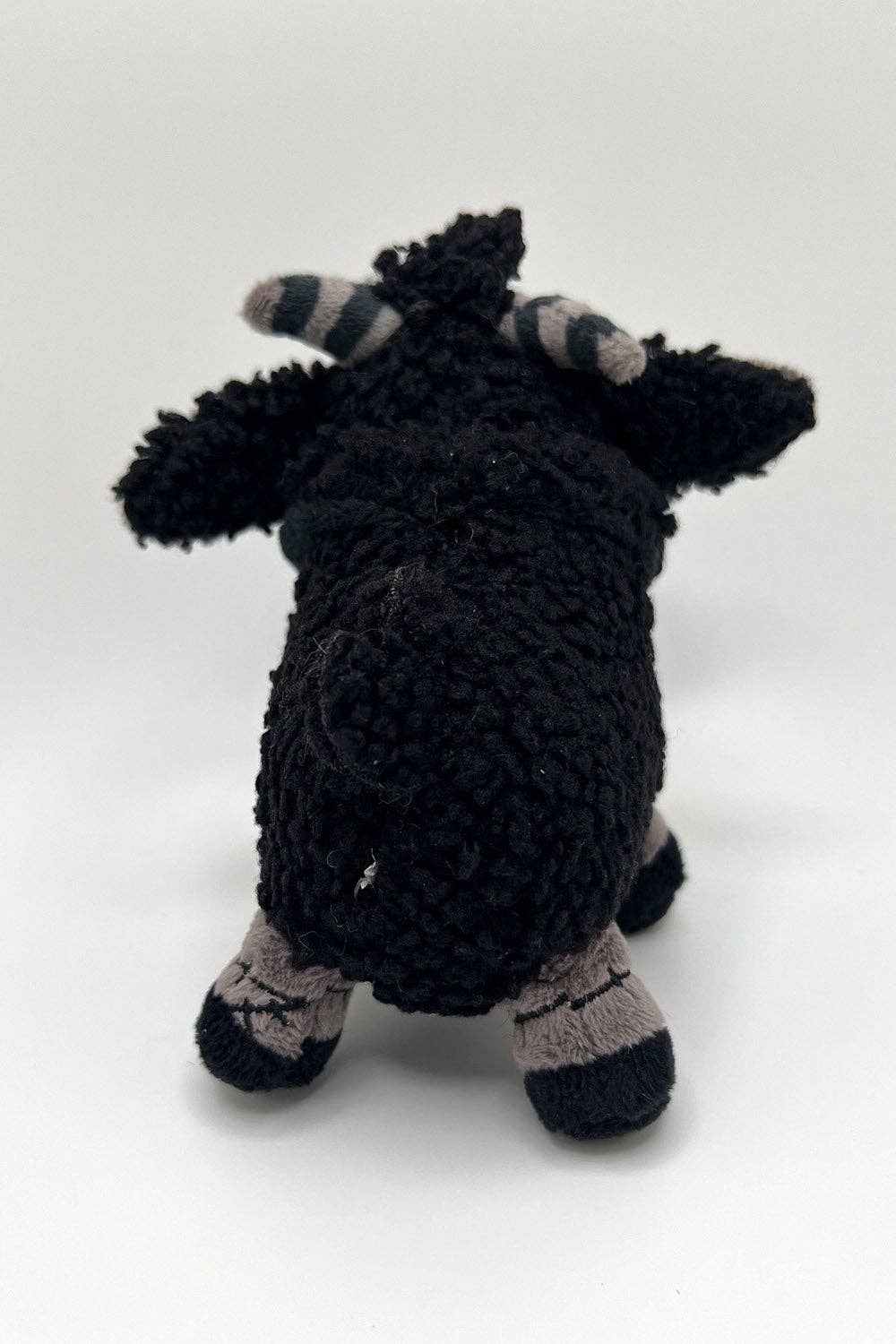 Black crochet toy with striped horns on a white background