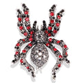 Spider-shaped brooch with red and black gemstones on a white background