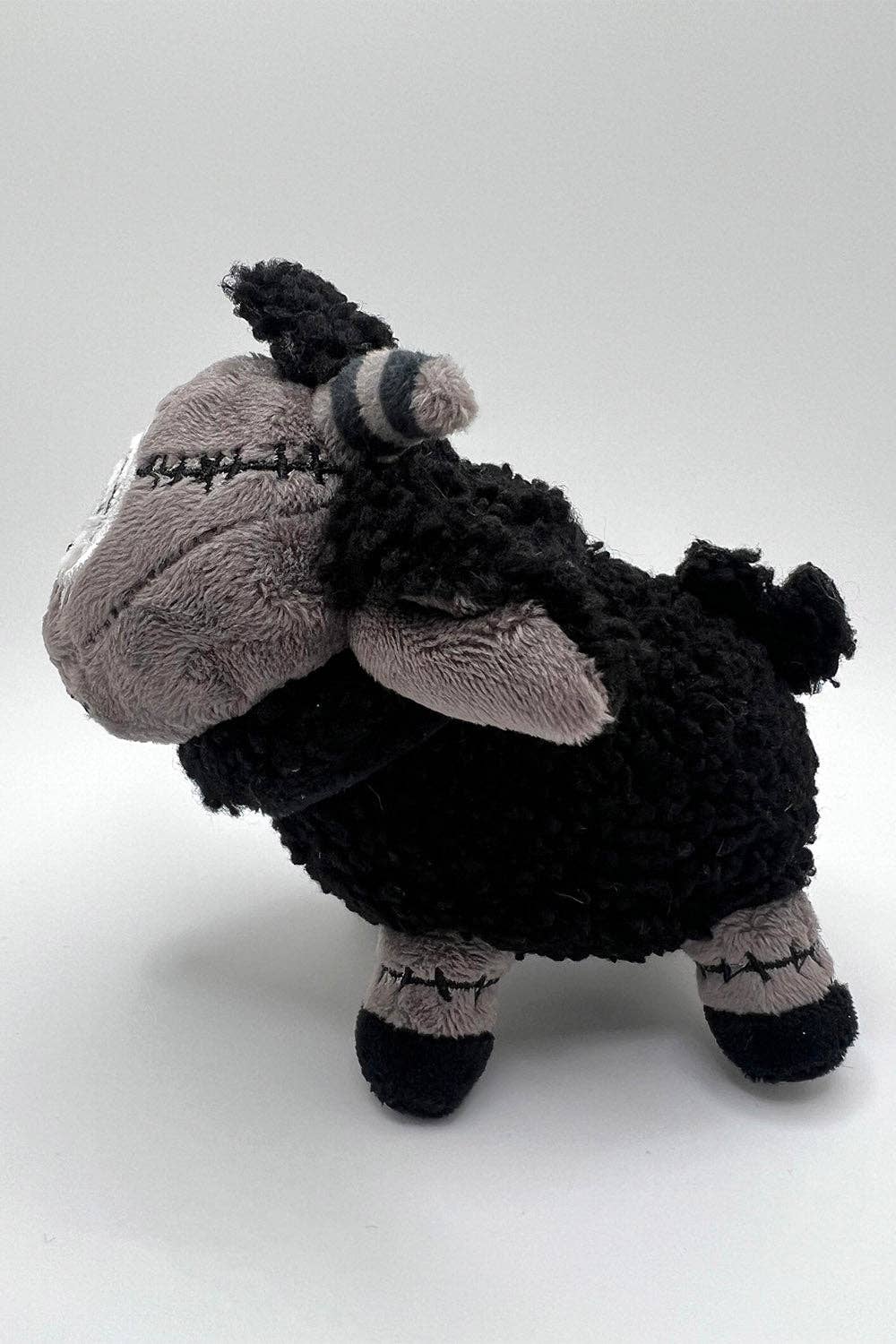 Plush toy sheep with a black and gray color scheme on a white background