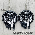 A pair of gothic-style dangle earrings with black circular pendants featuring a white angel illustration, shown against a white background with text indicating weight.