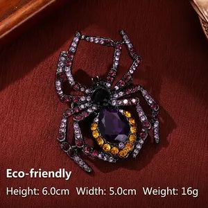 A spider-shaped brooch with black metal legs, purple gemstone center, and gold and clear rhinestone accents, displayed on a dark red textured surface with text overlay showing dimensions and weight.