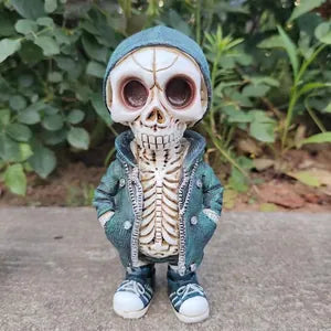 A skeleton figurine wearing a teal hooded jacket, white vest, and sneakers, standing outdoors on a concrete surface with green foliage in the background.