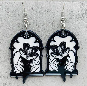 A pair of gothic-style dangling earrings with black and white floral arch designs and silver hooks, shown against a textured gray background.