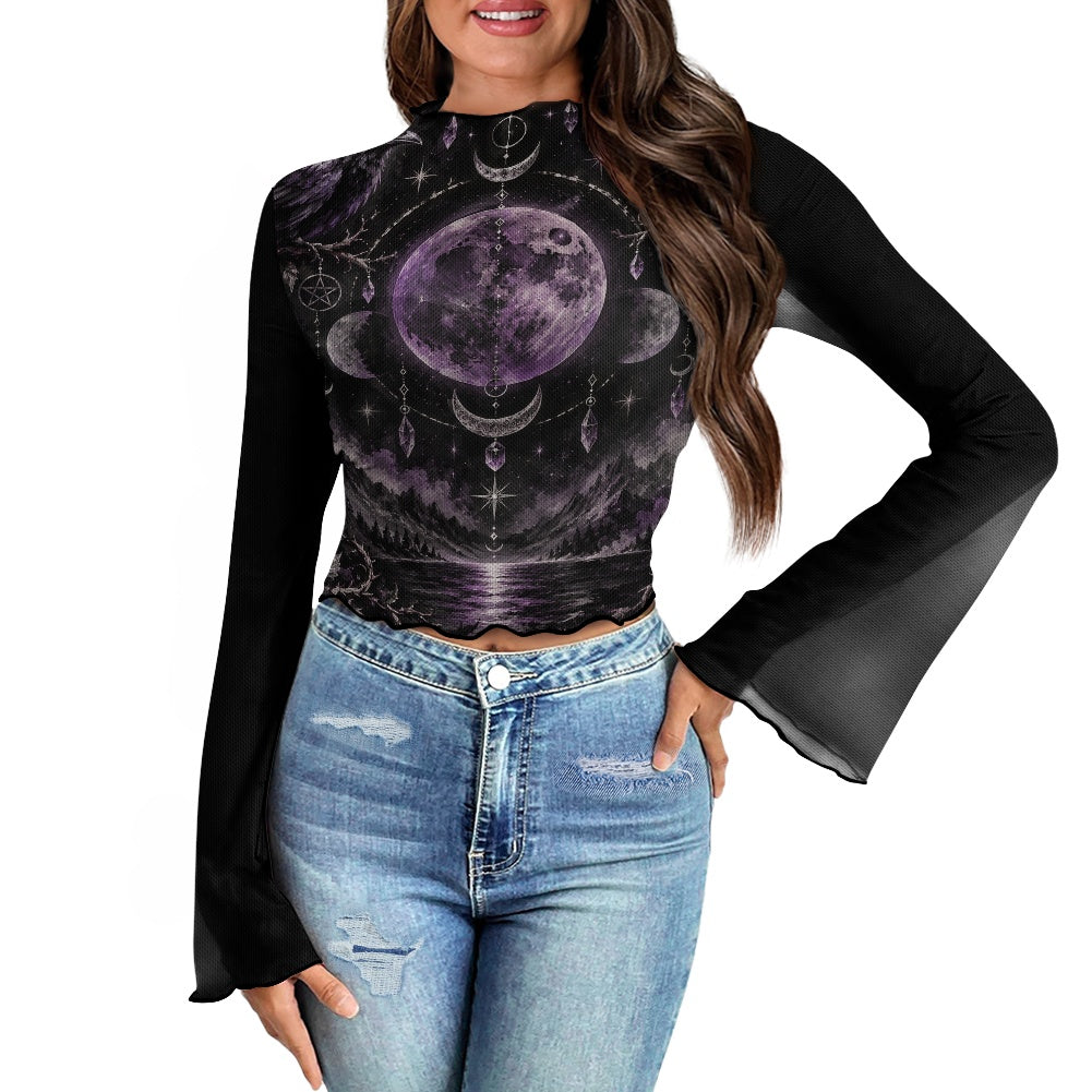 A woman wearing a black long-sleeve mock-neck crop top with a purple celestial moon print, paired with light-wash blue jeans, shown against a plain white background.