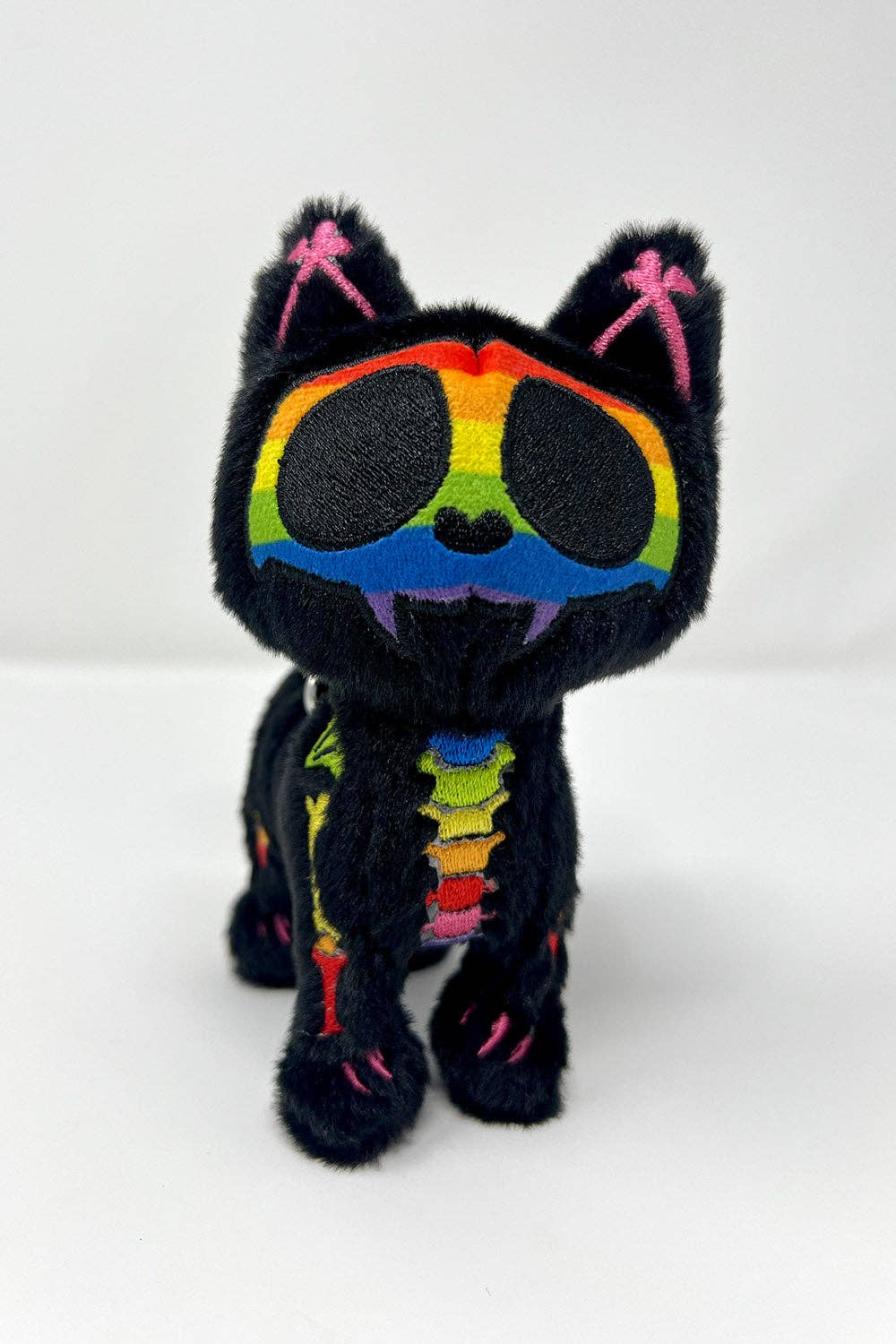 Black cat plush toy with rainbow skeleton design on a white background