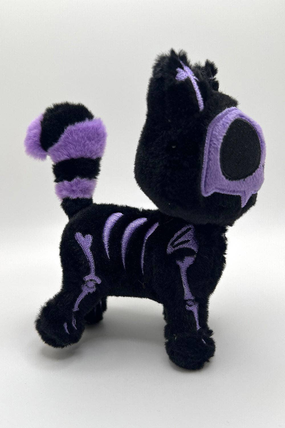 Black and purple plush toy with skeleton design on a white background
